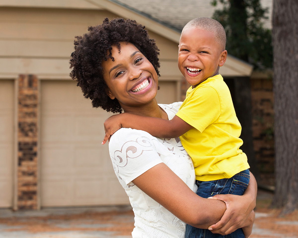 Smiling mother holding her son outside of a garage door