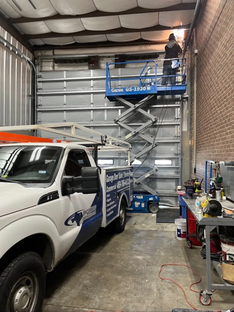 Worker on Lift Performing Emergency Garage Door Repair in Industrial Setting