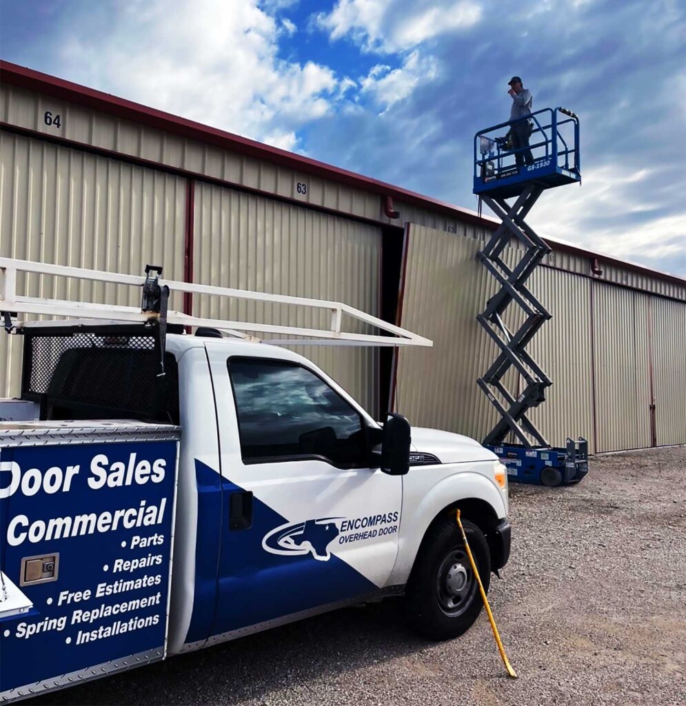 Technician on Lift Performing Emergency Garage Door Repair at Commercial Site