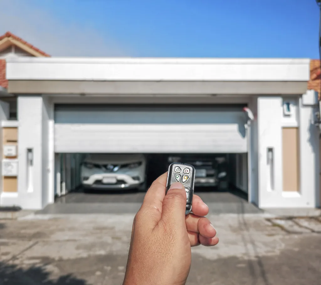 Hand Holding Remote in Front of Two-Car Garage Door Installation